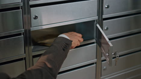 closeup hand open mailbox in apartment building. person in suit checking mail