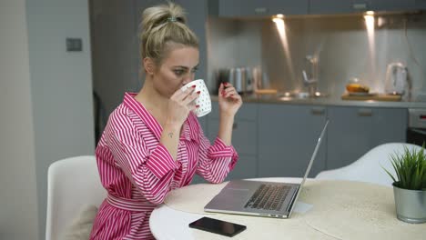 mujer bebiendo y usando laptop