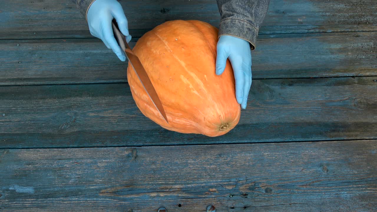 검은 칼로 큰 호박을 잘라내는 농부