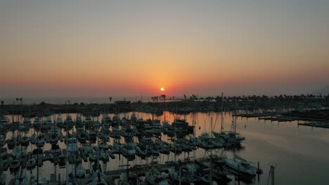 Drone-Asciende-Sobre-El-Puerto-Deportivo-Con-Barcos-Al-Atardecer-En-El-Paisaje-Marino