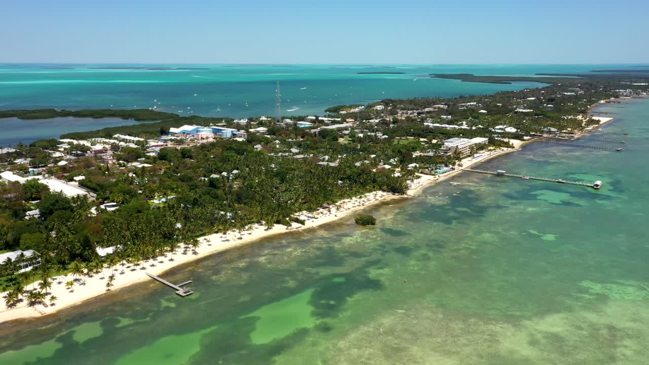 Aerial establishing of Lodge coastline with bright turquoise water and resort area, midday