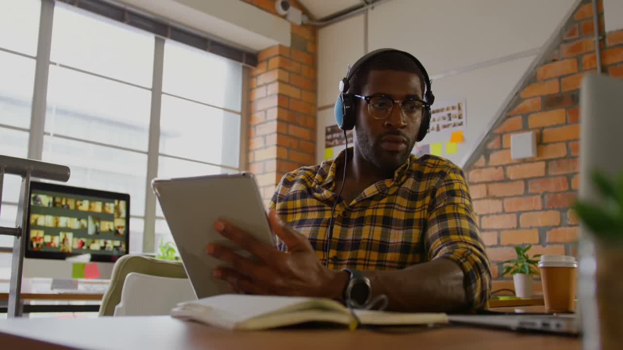 Male graphic designer listening to music while working at desk 4k