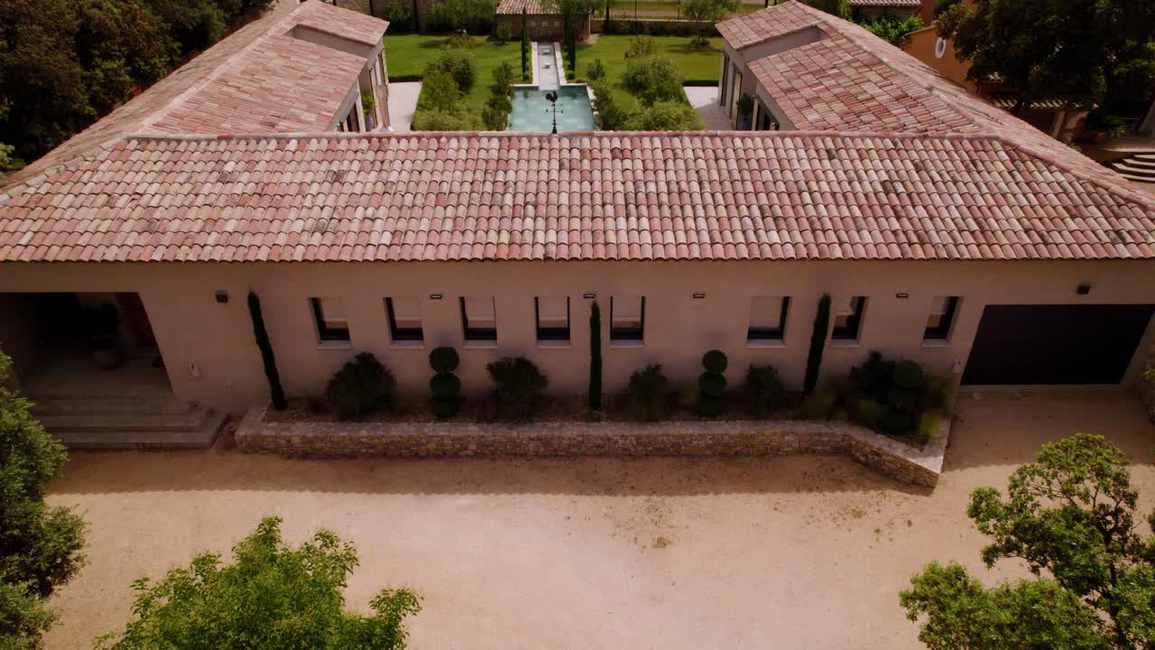Aerial View of a Proven&ccedil;al Roman-Style Villa with a Courtyard, Pool, and Garden, Revealing an Olive Grove through a Tilted Drone Shot