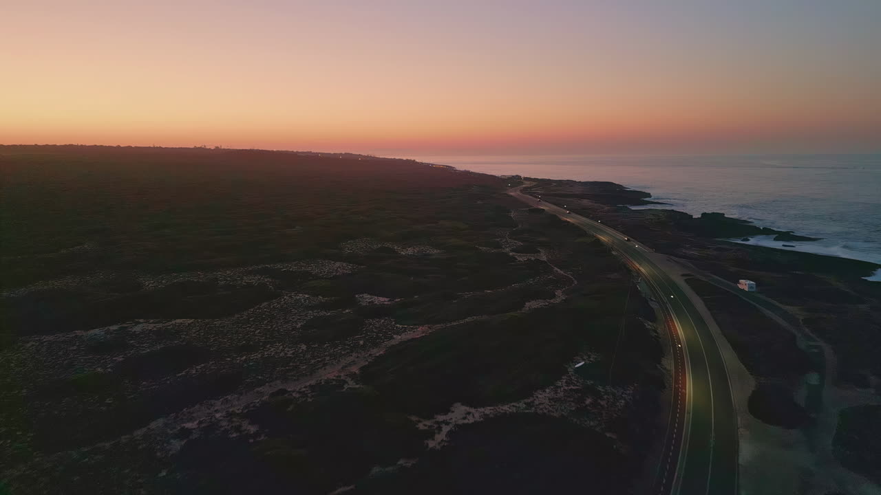 Breathtaking pink sunset sky over coastline drone view. Road running seashore