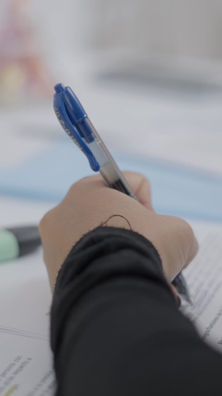 Close-up of a hand writing on a document with a blue pen