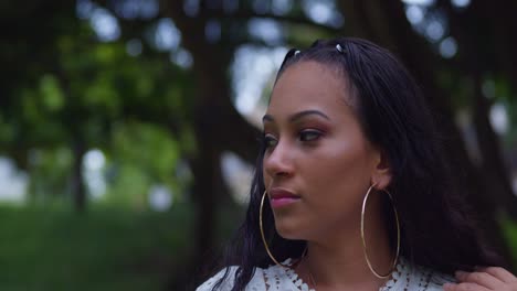 amazing facial close up of a young female with a nose ring and hoop earings at a park