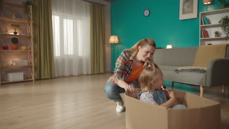 madre e hija jugando en una caja de cartón