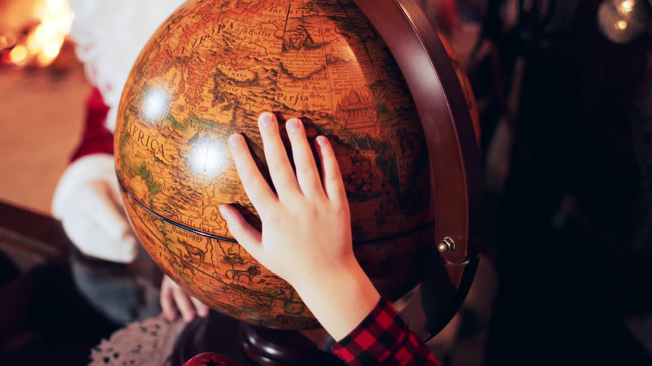 The boy puts his hand on an old retro globe with countries