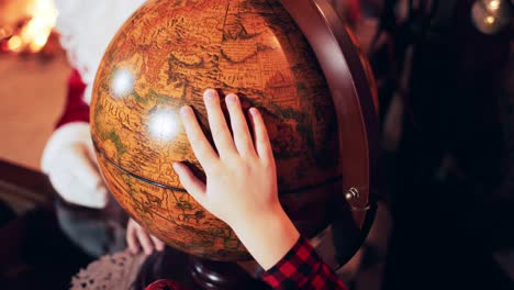 the boy puts his hand on an old retro globe with countries