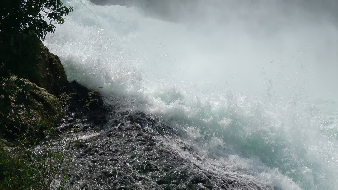 Scenic view of Rhine Falls with turbulent water, white foam and heavy mist rising above the rocks, filmed near Schaffhausen in the canton of Schaffhausen, Switzerland