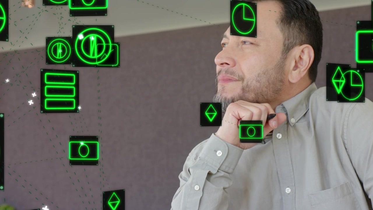 Mature man pausing writing turning to laptop viewing floating green data icons while analyzing tech