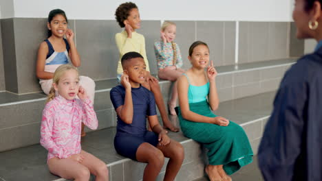 children in swimsuits sitting by the pool during a swim class