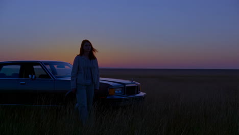 woman and car in a field at sunset