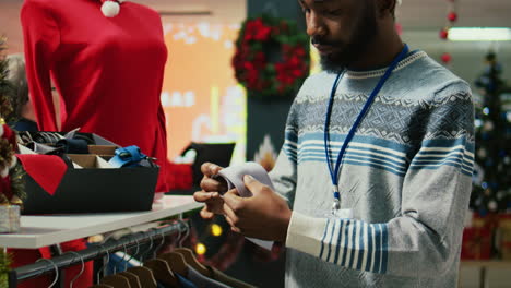 portrait close up shot of african american employee arranging stylish neckties in christmas decorated shopping mall fashion boutique, making sure they are ready for arriving customers