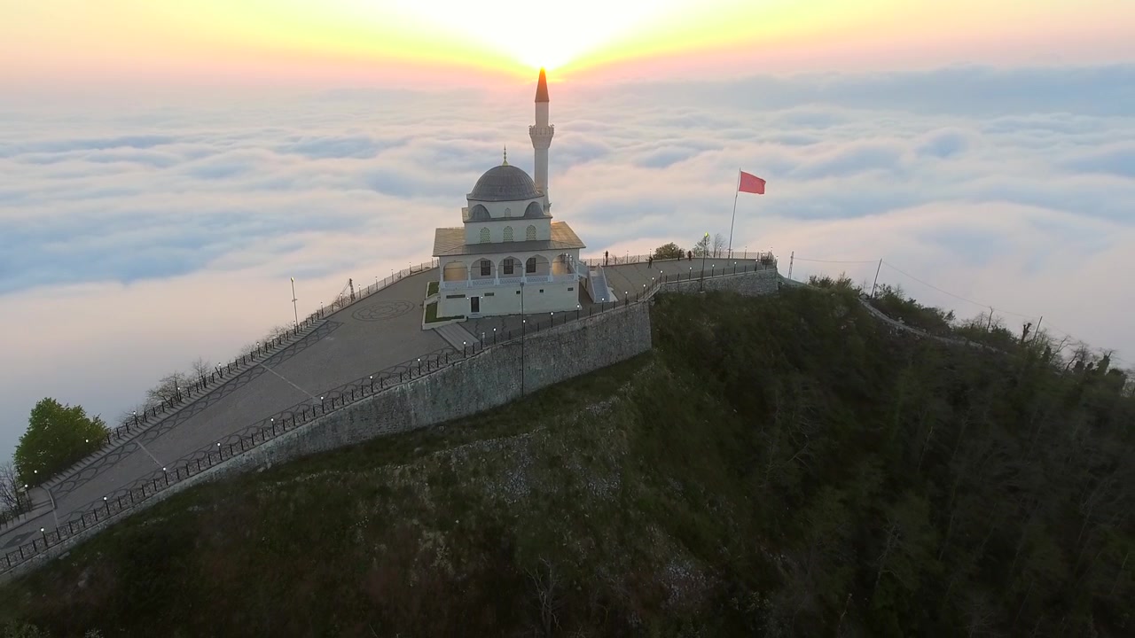Luchtfoto van moskee op bergtop boven de wolken bij zonsondergang