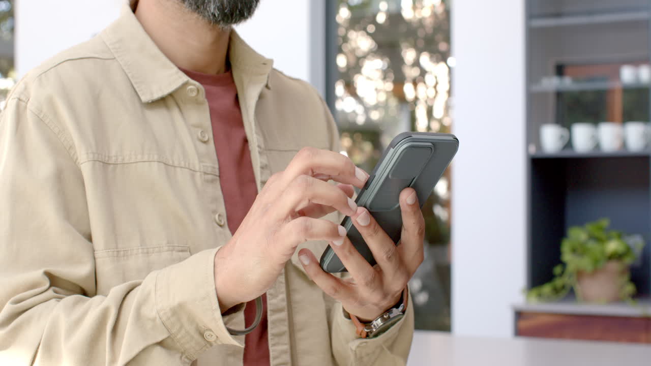 Typing message, man using smartphone in modern home environment