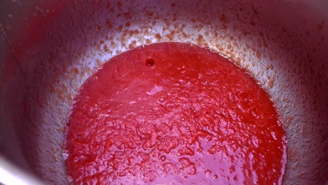 freshly pressed tomato sauce dripping on an aluminum bucket