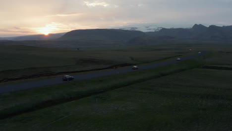 Vuelo-De-Drones-Con-Vista-Aérea-Sobre-El-Tráfico-De-La-Carretera-De-Circunvalación-Vespertina-En-Islandia.-Ojo-De-Pájaro-De-Los-Coches-Que-Conducen-Por-Una-Carretera-Recta-A-Través-Del-Valle-Herboso-De-Las-Tierras-Altas-Al-Atardecer