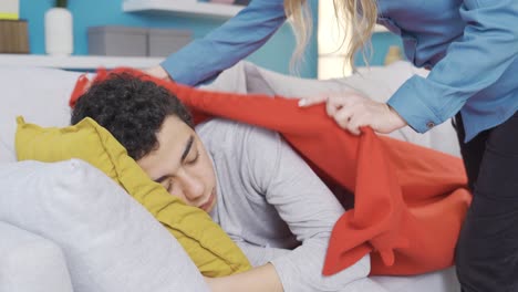 el amor de la madre. la madre cubriendo a su hijo que se quedó dormido en el sofá con una manta.