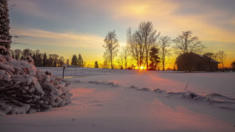 Zeitraffer-Einer-Verschneiten-Landschaft-Mit-Bäumen-Und-Einem-Holzhaus,-Auf-Das-Die-Sonne-Im-Goldenen-Sonnenuntergang-Fällt