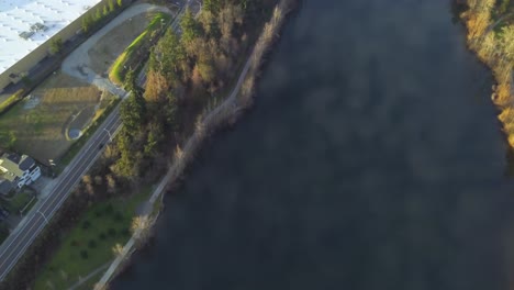 toma aérea de drones del lago wapato con reflejos de cielo azul y nubes esponjosas en el agua y la concurrida autopista i-5 en tacoma, washington en una tarde brillante