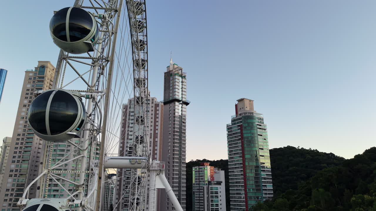 Aerial closeup fly spinning Ferris Wheel, amusement in Balneario Camboriu of Brazil with resorts background