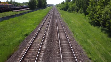 бесконечные железнодорожные пути в ярком зеленом пейзаже, стремительный полет над рельсами