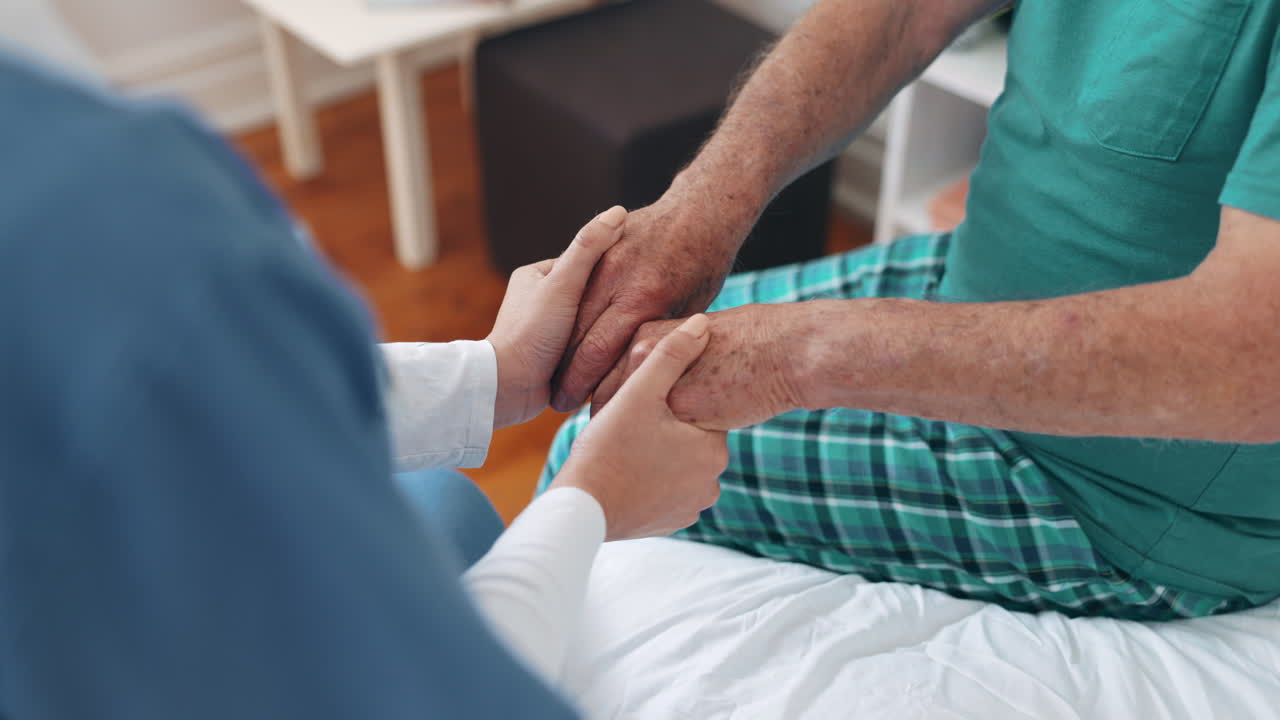 Infermiera che tiene le mani e sostiene il paziente a letto.