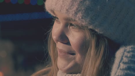 girl in knitted mittens and hat smiles on dark background