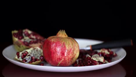 pomegranate fruit and red seeds served on white plate, antioxidant vitamins