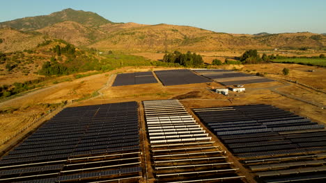 aerial view of a solar power facilities in romeral, chile. rows of solar panels set against dry hills and evening light. renewable energy landscape in south america