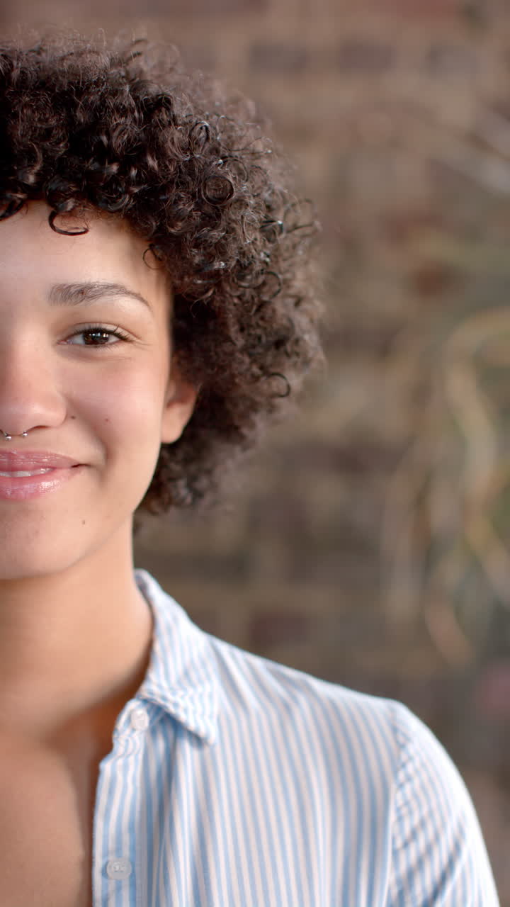 Vertical video of portrait of happy biracial casual businesswoman in office in slow motion