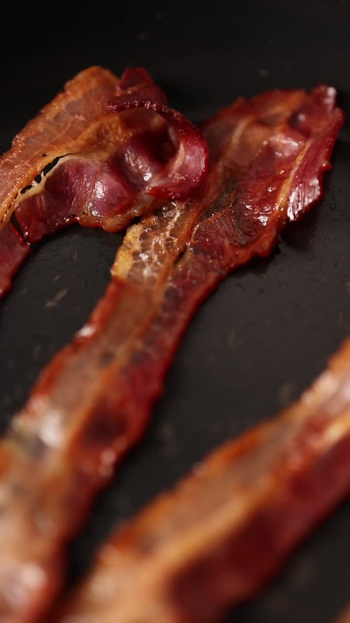 Primo piano di pancetta che sfrigola in una padella calda