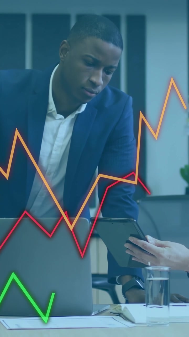 Vertical video: Man entering data on laptop, tablet for business report, colleague causing graphs