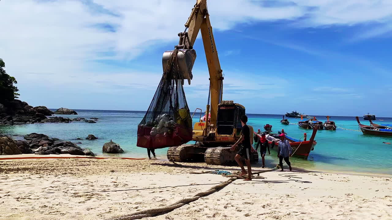 Time-lapse shot of people working by the boat at the beach line with an excavator.