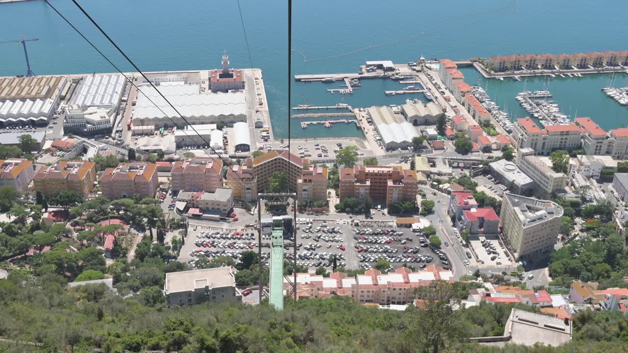 View from inside a cable car ascending over Gibraltar, showcasing the city, harbor, and sea