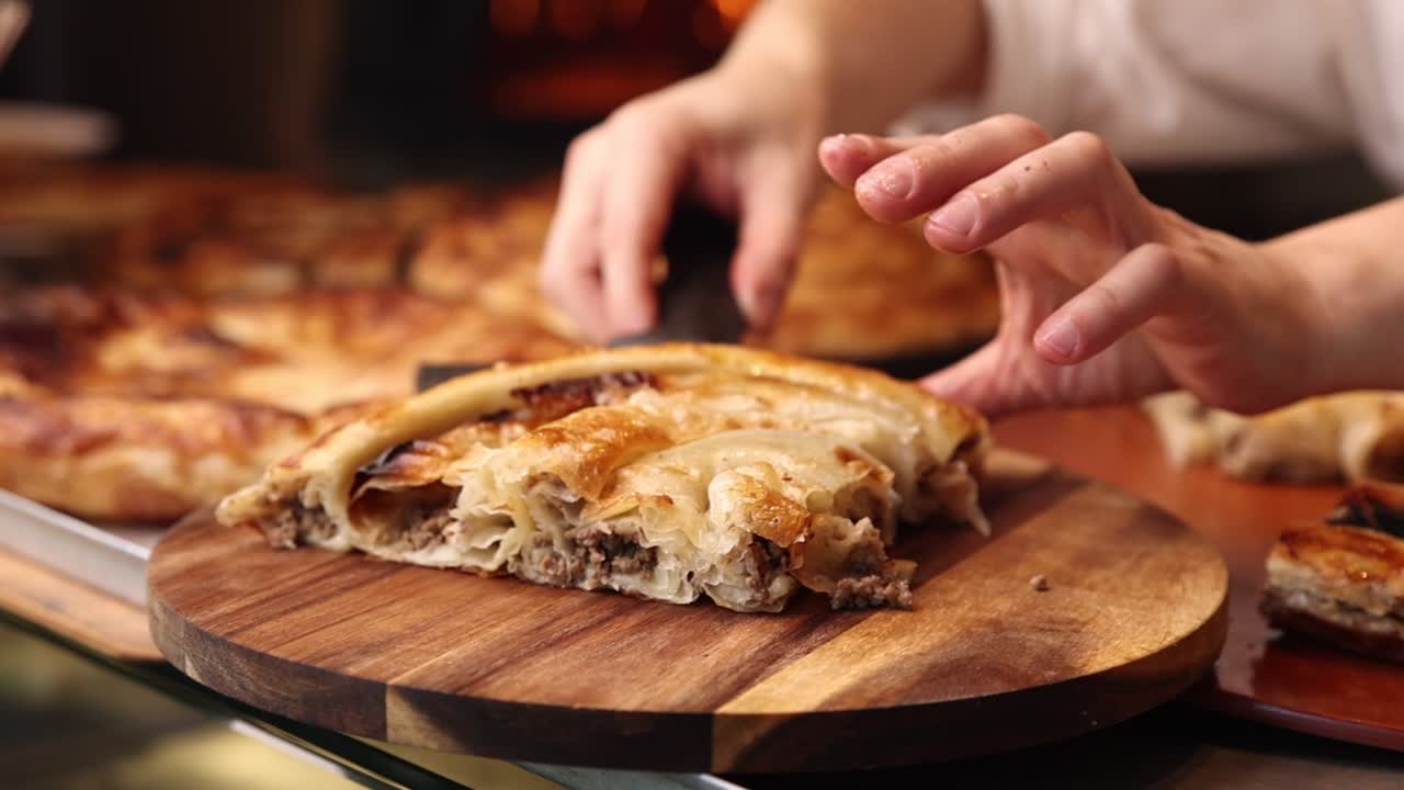 Chef's Hands Serving a Delicious Slice of Traditional Meat Burek