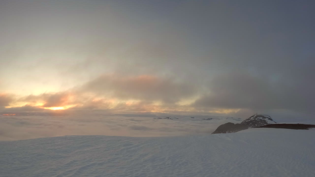 午夜的太陽和移動的雲在斯堪的納維亞北部的山峰上