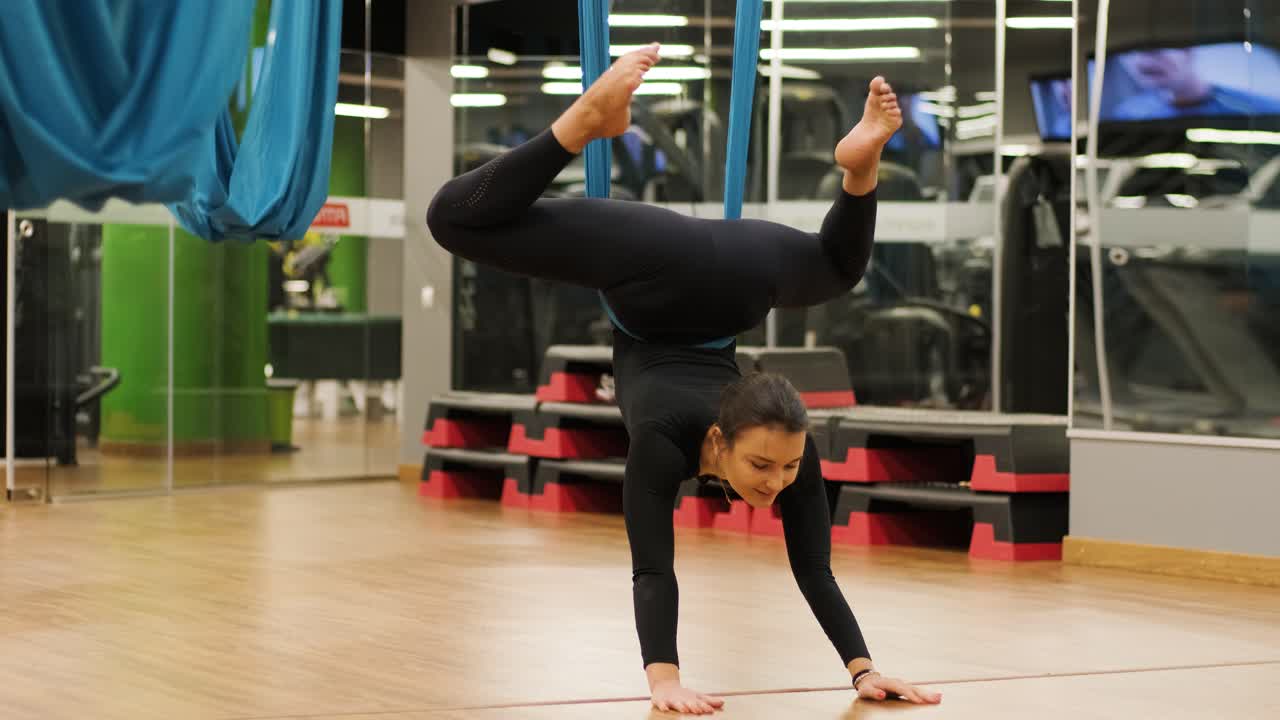 Donna attraente che fa esercizi di stretching aero yoga in amache in studio fitness. Stile di vita sano per le donne. Palestra di allenamento