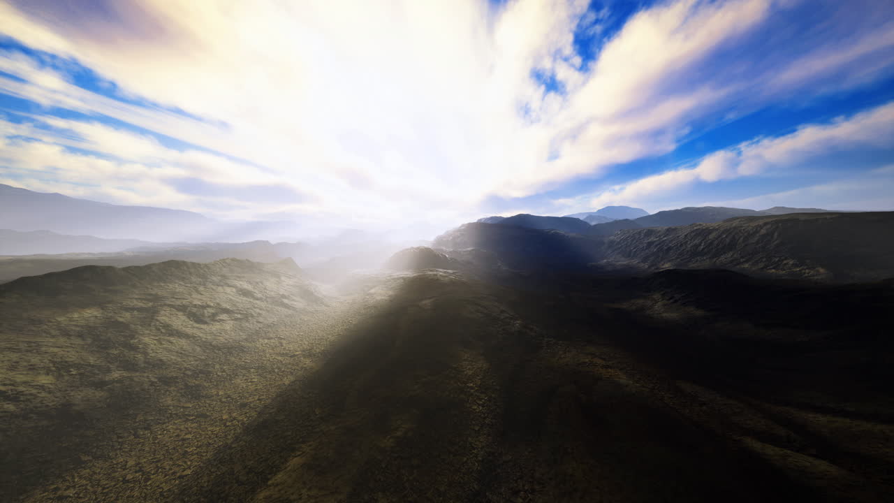 Bright light breaks through clouds over rugged mountain landscape at dawn