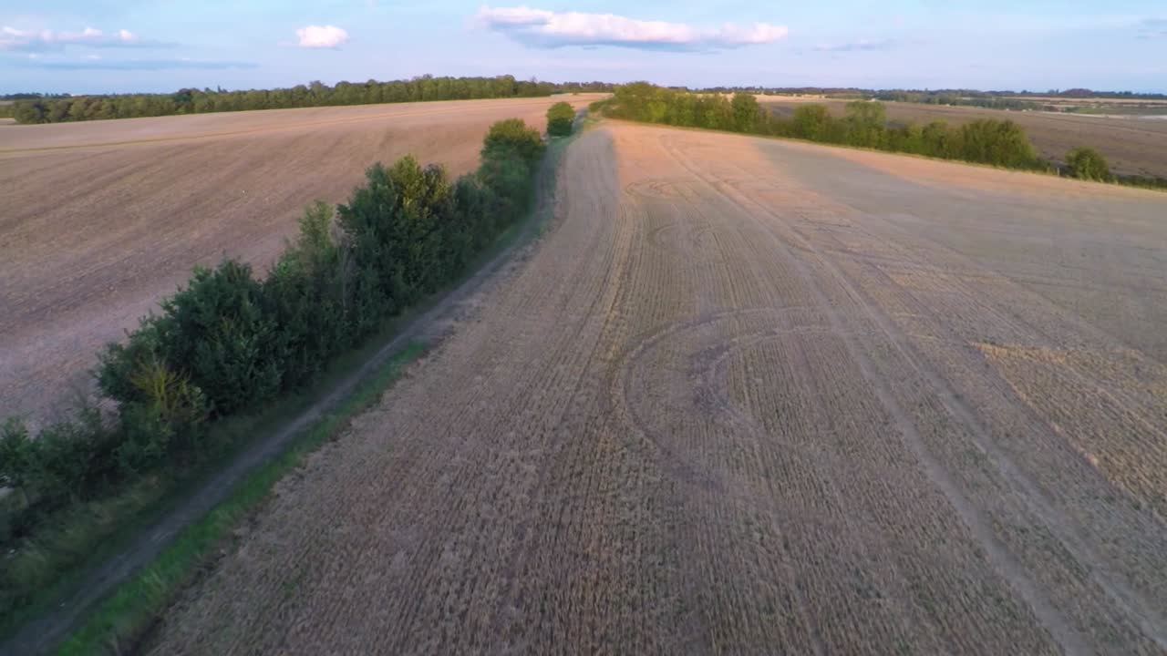 Slowly flying up a beautiful walking path, revealing rolling fields and farmland