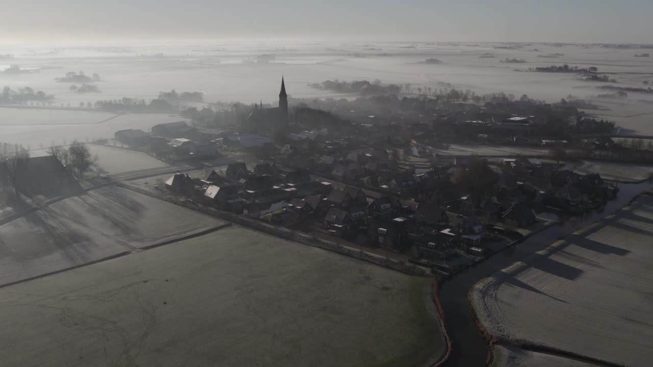 Schilderachtige luchtfoto van mistig dorp met kerk in Tjerkwerd, Friesland, Nederland
