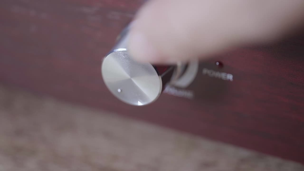 Mão ajustando o botão de volume em um amplificador de áudio