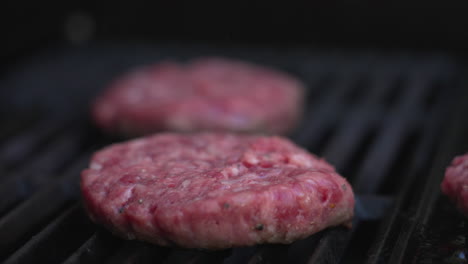 pull focus close up shot between two burger patties sizzling on a bbq