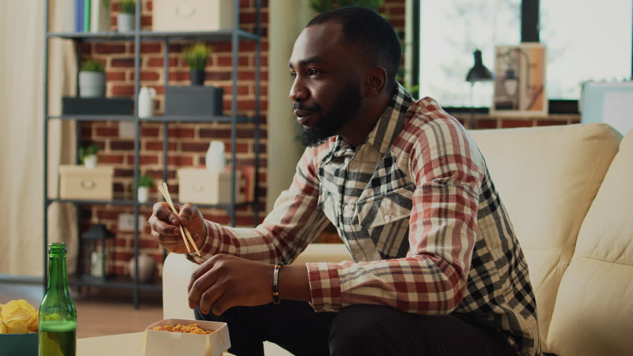 Happy relaxed man eating noodles at home