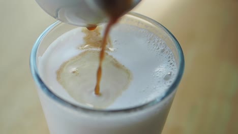 pouring espresso into a glass of milk