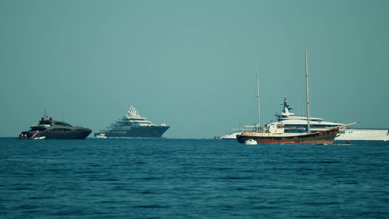 Super yacht di lusso e imbarcazioni che navigano in acque oceaniche calme e blu sotto un cielo sereno, rappresentando viaggi di piacere e uno stile di vita marittimo.