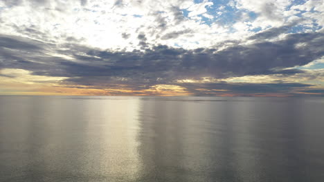 AERIAL:-Flying-Backwards-Above-Baltic-Sea-During-Golden-Hour-with-Majestic-Horizon-with-Orange-and-Blue-Colours-in-the-Sky