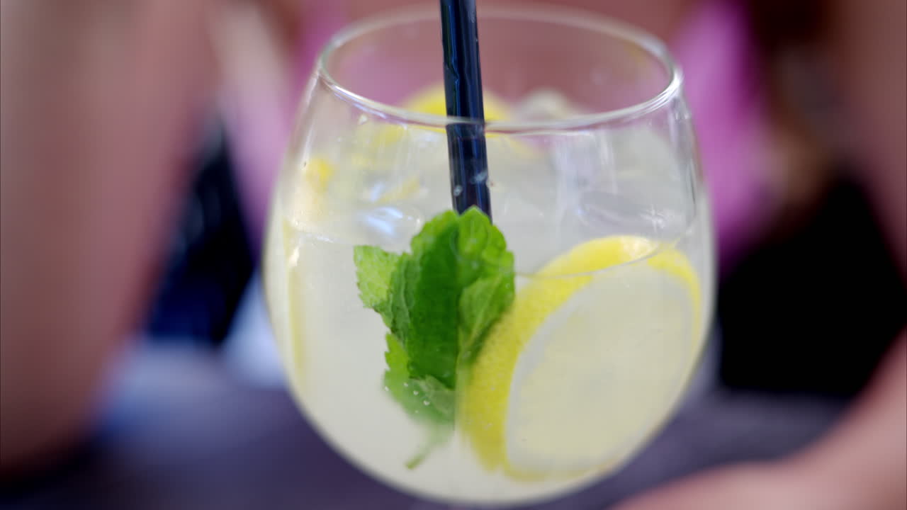 Donna che beve un bicchiere di limonata con menta e ghiaccio, slow motion