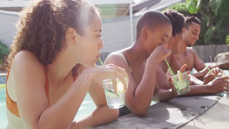 grupo de diversos amigos masculinos y femeninos que toman bebidas riéndose en la piscina
